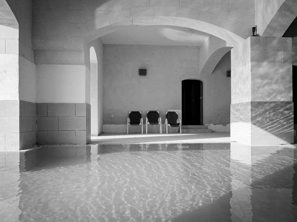 Architectural indoor bathing pool surrounded by arches and stone benches
