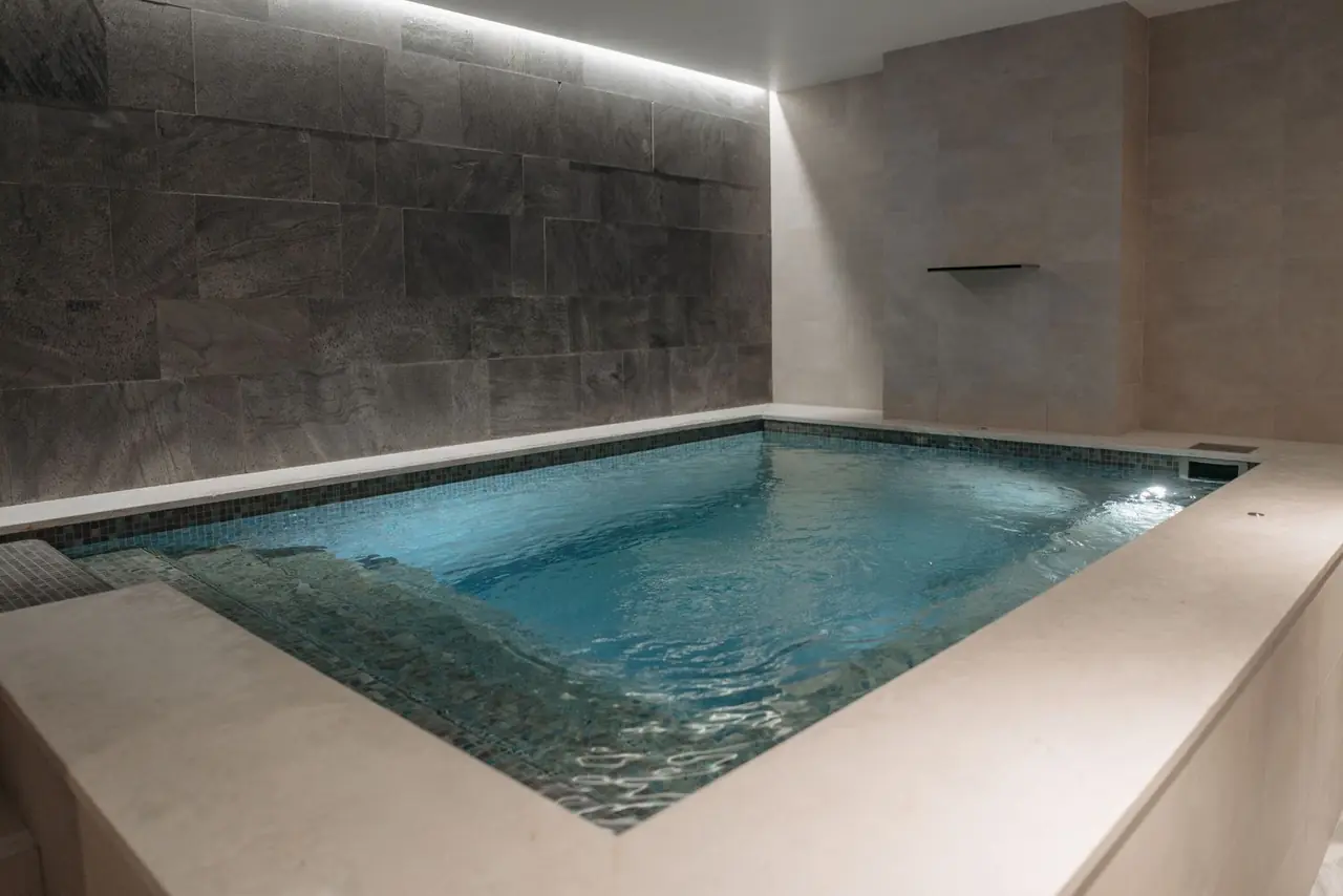 Stone tile architecture reflecting calm water inside an indoor bathing retreat