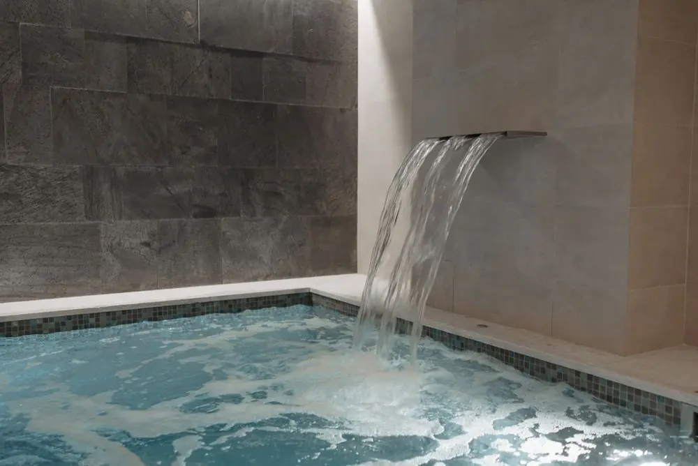Tranquil indoor pool with arched architectural stone walls and gentle water reflections